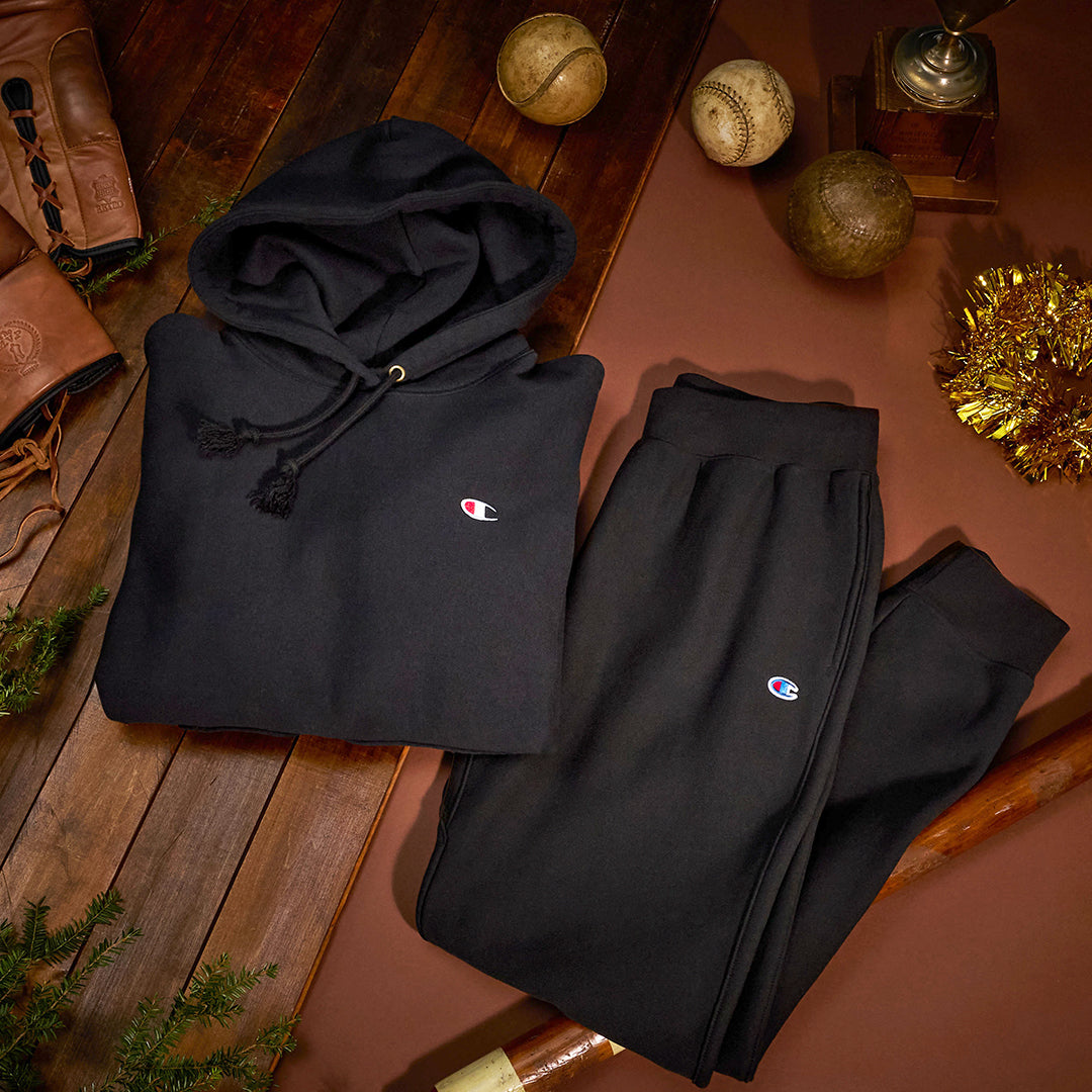 black hoodie and pants laid out on a wooden floor with baseball and Christmas decorations.