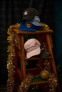 Collection of hats on a wooden stool with tinsel, against a dark background