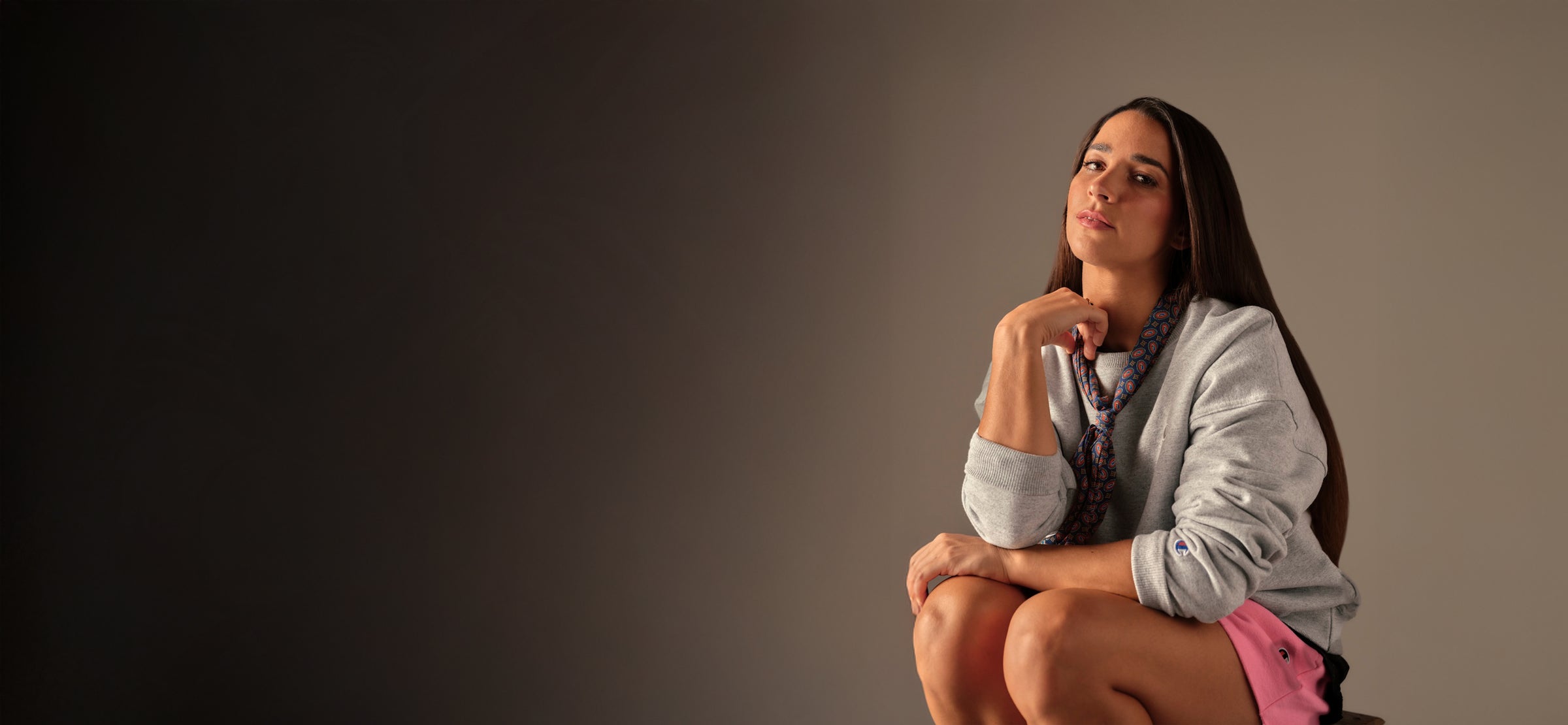 Woman sitting on a stool against a plain background