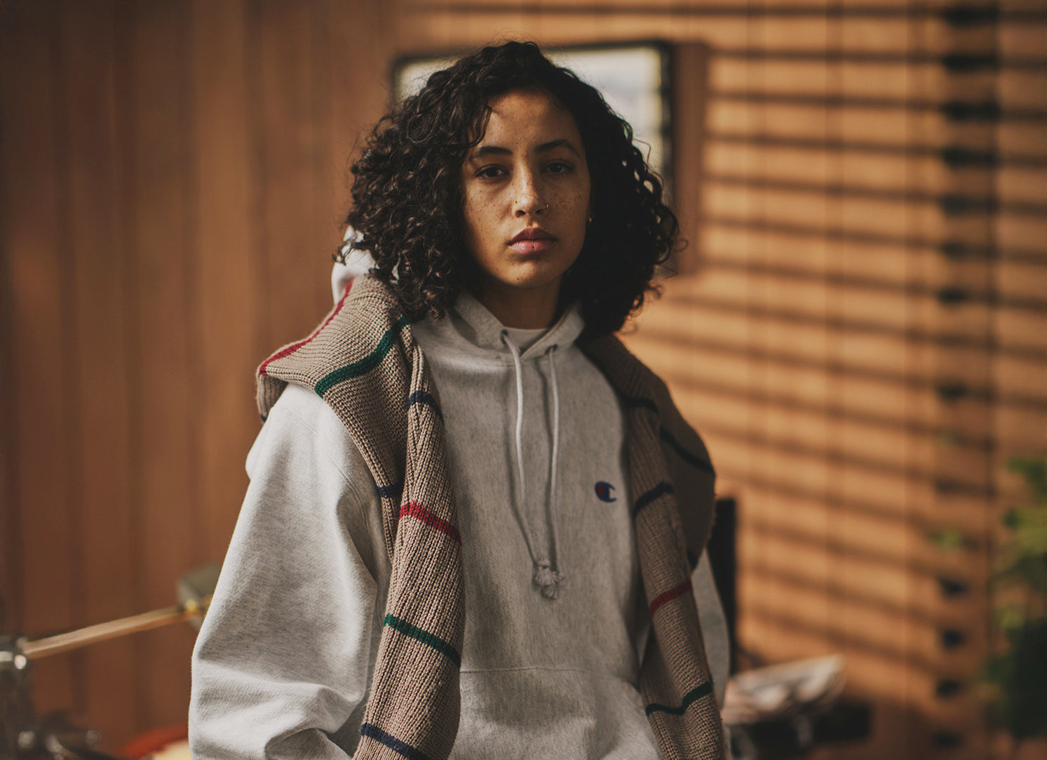 Person wearing a plaid jacket over a reverse weave hoodie in a room with wooden walls.